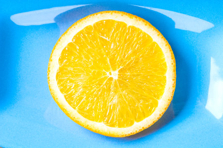A top view of ripe vitamin orange fruits slice on a blue backgroundの写真素材