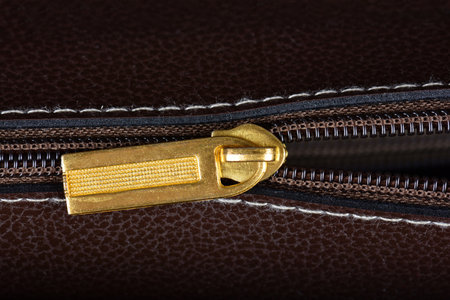 A close up of a brown leather bag zipper
