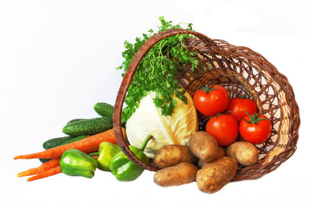 A set of fresh vegetables in a wicker basket on a white backgroundの写真素材