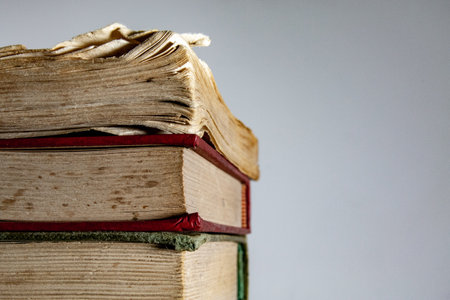A closeup shot of old books stacked on each other against a gray backgroundの写真素材