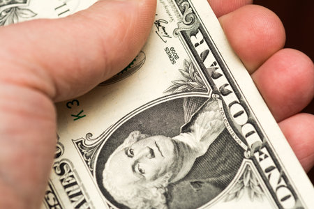 A hand holding a bunch of US dollar banknotes