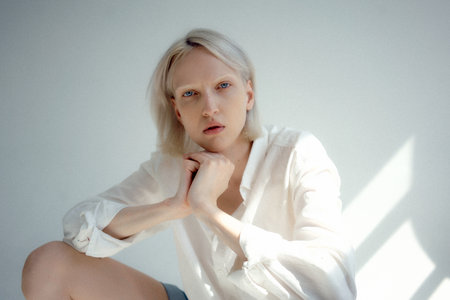 An attractive Russian blonde female wearing a white shirt posing in a studio