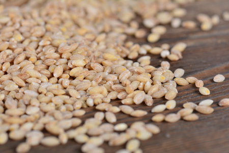 A selective focus shot of a pile of pearl barley grains on a wooden tableの写真素材