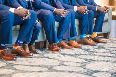 A view of the males wearing suits sitting on a couch wearing funny socks and beautiful oxford shoesの写真素材