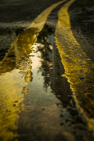 A vertical shot of the wet street with yellow linesの写真素材