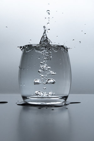 A vertical shot of a glass of water with splashes