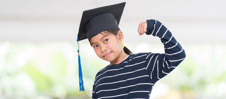 A shallow focus shot of a happy Thai kid with a graduation hat