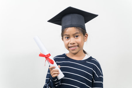 A happy Thai kid with a graduation hat and diploma isolated on white backgroundの写真素材