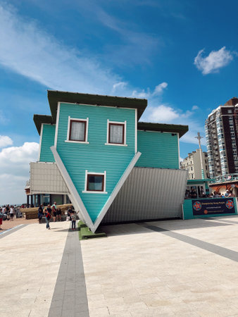 An upside down house against a cloudy blue sky in Brighton, United Kingdomの写真素材