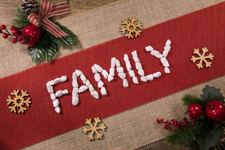 A top view of the Famil word with wooden snowflakes and pine decorations on a red linen fabricの写真素材