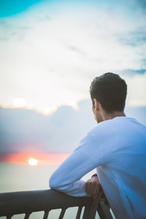 A vertical shot of a man on the sunset sky backgroundの写真素材