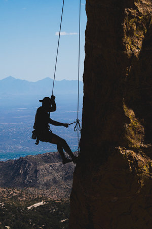 A vertical shot of a rock climber cleaning a route on Mount Lemmon in Tucsonの写真素材