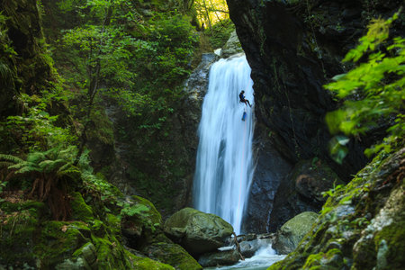 A person climbing up a waterfall in a forest