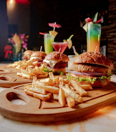 A vertical shot of fast food with cocktails on wooden cutting boards