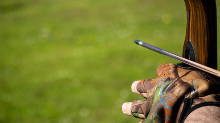 A closeup shot of a male's hand on an arrow and a bow