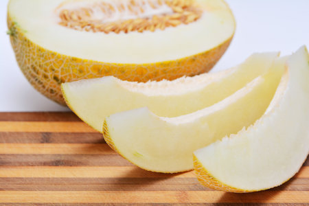 Fresh ripe melon and a wooden cutting board isolated on a white backgroundの写真素材