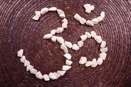 The Om sacred symbol written with white stones over a rustic purple textureの写真素材