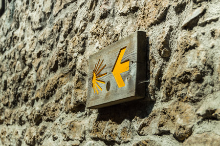 A closeup of Scallop symbol of Santiago's road with an arrow on a stone wall in Cantabria, Spain.の写真素材