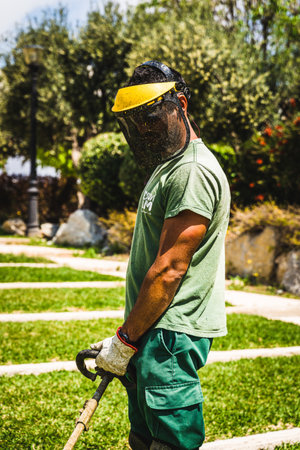 A worker in a special uniform doing lawn mowing in the yardの写真素材