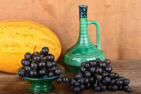 An old potter jug and fruits on a wooden tableの写真素材