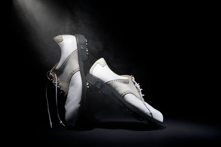 A closeup of a pair of brogue shoes under the lights against a black backgroundの写真素材