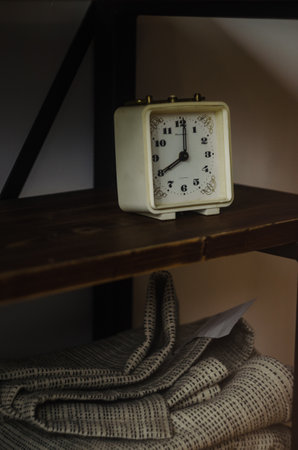 A closeup of an old classical clock on a wooden shelfの写真素材