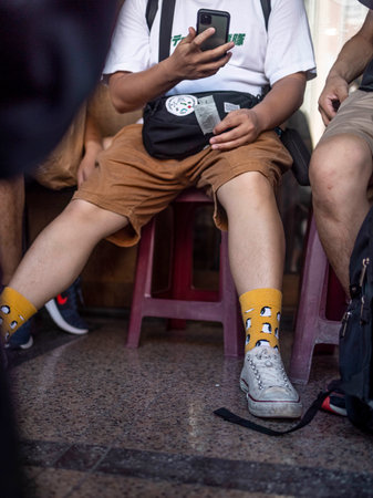 A vertical closeup shot of a male sitting on a chair with yellow penguin socksの写真素材