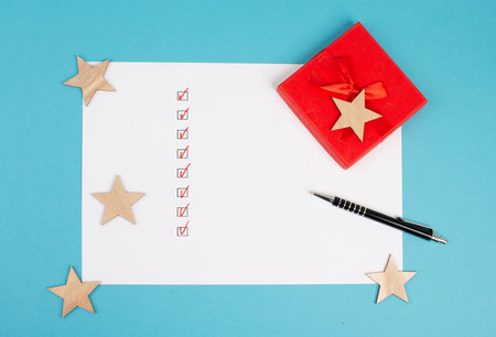 Empty paper, pen, red colored gift, stars, background for christmas, wintertime, copy space, holidays, check marksの写真素材