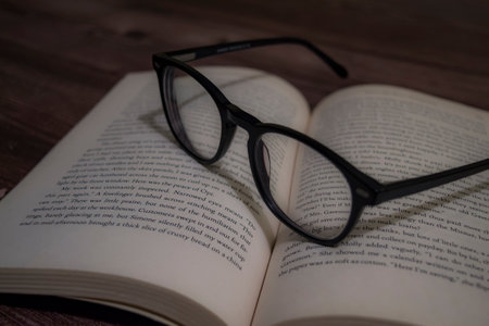 A closeup shot of a reading glass on an opened bookの写真素材