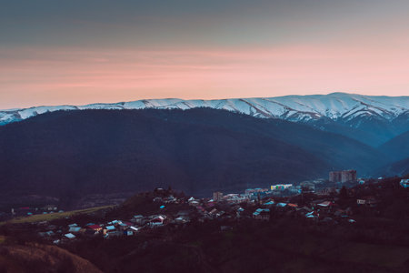 A beautiful view of a landscape with mountains and a village at sunset