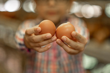 A closeup shot of a boy holding two eggs with blurred backgroundの写真素材