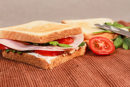 A closeup of sandwiches with toast bread, tomatoes, ham, and parsley.の写真素材