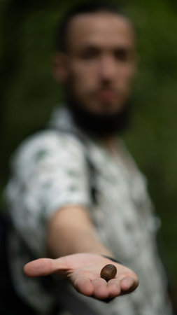 A vertical shot of a man holding an acornの写真素材