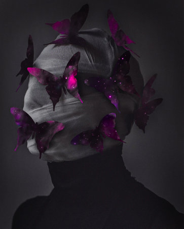 A vertical shot of a person covered in a fabric decorated with vibrantly colored butterfliesの写真素材