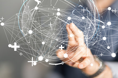 A man tapping on a 3D rendering of a globe hologram with interconnected dotsの写真素材