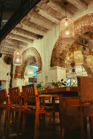 A vertical shot of the interior of a restaurant with a wooden table and chairs with chandelierの写真素材