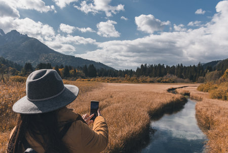 A woman taking photos of autumn landscape at Zelenci nature reserve in Sloveniaの写真素材