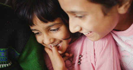 A closeup shot of the smiling faces of two South Asian kidsの写真素材