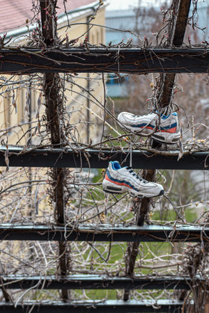 A vertical shot of sneakers hanging on the wooden net roofの写真素材