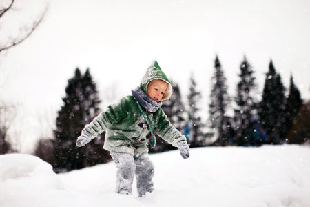 A cute Caucasian kid playing outdoors in the snow