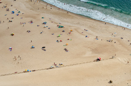 An aerial shot of a wavy and sandy beach of the sea with tourists, Portugalの写真素材