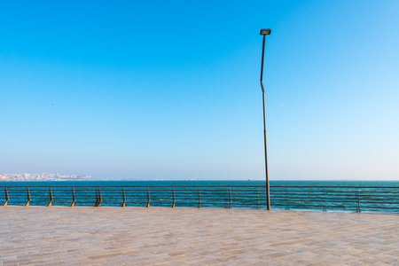 A beautiful scene of a fence in sandy beach to seaside with a light blue sky on the horizonの写真素材