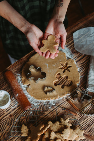 A top-view of a female baker's hands cutting ginger cookies for Christmas on a rustic wooden boardの写真素材