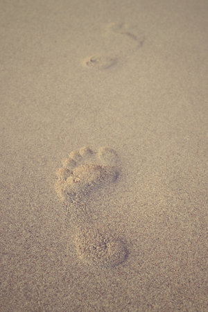 A vertical shot of footprints on the beach