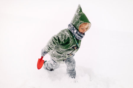 A cute cheerful Caucasian kid playing outdoors in the snow