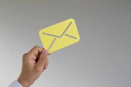A man's hand holding a 3d rendered email iconの写真素材