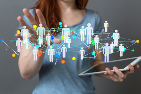 A hologram of a network of people working as a team, projecting from a woman's tabletの写真素材