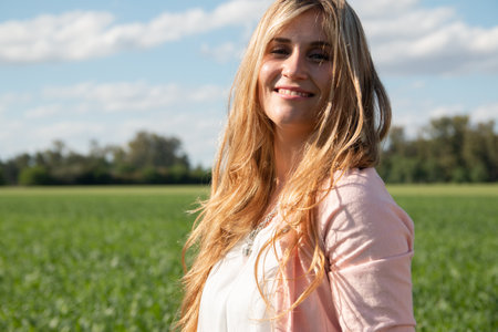 An attractive Argentinian woman walking on an agricultural field under a bright sunny skyの写真素材