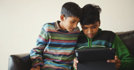 A shallow focus of two South Asian siblings browsing the internet on a tabletの写真素材