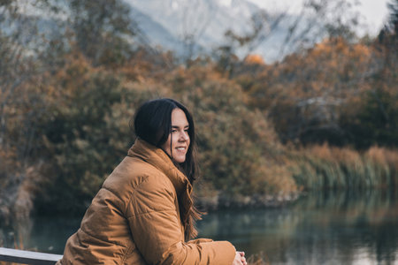 A young female admiring beautiful autumn nature at Zelenci nature reserve in Slovenia